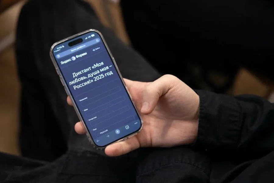 Участник проходит диктант со смартфона на церемонии открытия